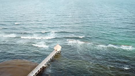 Aerial-View-Of-Fishing-Pier-In-Quintana-Roo,-Mexico-With-Sea-Waves-Splashing-In-Slow-Motion
