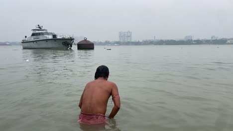 Vista-De-Cerca-De-Un-Hombre-Dándose-Un-Chapuzón-En-El-Río-Ganges-Al-Amanecer-En-Kolkata,-India,-Con-La-Vista-Del-Barco-En-El-Fondo