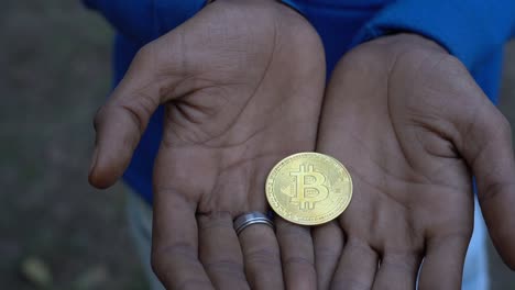 Close-up-shot-of-dirty-bitcoin-cryptocurrency-gold-in-the-hands-of-an-dirty-man