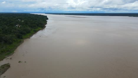 Vista-Aérea-Que-Avanza,-Vista-Panorámica-Del-Agua-Marrón-Del-Río-Amazonas-En-Colombia,-Cielo-Azul-Brillante-En-El-Fondo