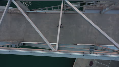 Birdseye-aerial-view-above-lone-male-pedestrian-walking-across-harbour-bridge
