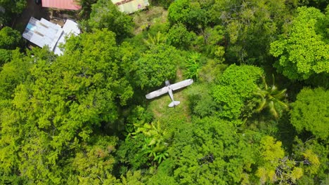 Birds-eye-view-ascending-shot,-scenic-view-of-a-plane-wreck-in-the-middle-of-the-amazon-forest-in-Colombia