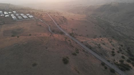 Aerial-view-around-a-road-in-the-highlands-of-Golan-Heights,-sunset-in-Israel---circling,-drone-shot