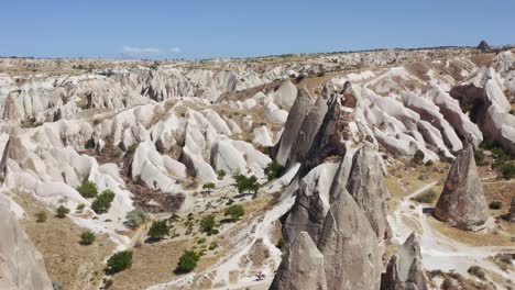 Aerial-view-of-the-town-Göreme-with-rock-houses-in-front-of-the-spectacularly-coloured-valleys-nearby