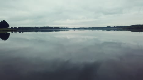 Thülsfelder-lake-near-dam-low-drone-flight-above-reflecting-water-4k-cloudy