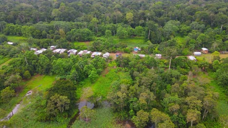 Aerial-view-moving-forward-shot,-scenic-view-of-a-small-village-in-the-amazon-rain-forest-in-Colombia,-tall-trees-in-the-background