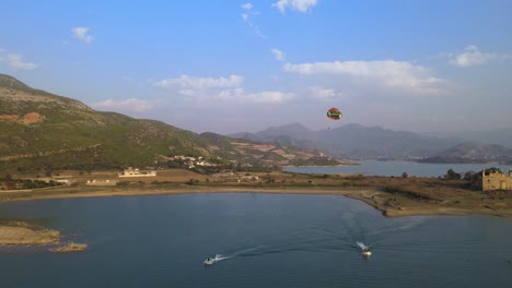 Man-enjoying-parasailing-flight-or-ride-above-the-lake-with-natural-background