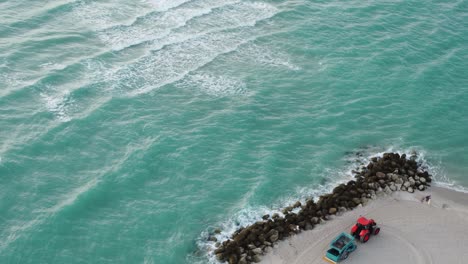 Ocean-waves,-tractor-and-rocks-on-the-beach-of-Miami,-Florida