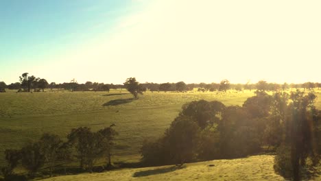 Establishing-aerial-shot-of-sunshine-over-grass-covered-plian-and-hills,-Culla-Victoria-,-Australian-rural-landscape