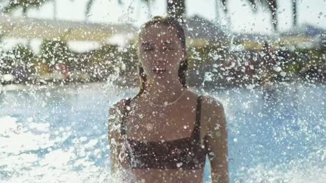 Schöne-Frau,-Die-An-Einem-Heißen-Sommertag-Einen-Kleinen-Wasserfall-In-Einem-Schwimmbad-Genießt