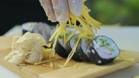Close-up-shot-of-fresh-Japanese-sushi-on-plate-with-restaurant-chef-decorating-rolls-with-chips-serving-preparing