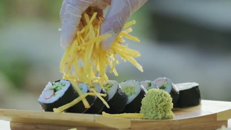 Close-up-shot-of-fresh-Japanese-sushi-on-plate-with-restaurant-chef-decorating-rolls-with-chips-serving-preparing