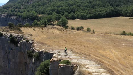 Risky-mountain-bike-descent-very-close-to-a-canyon-wall-edge,-aerial