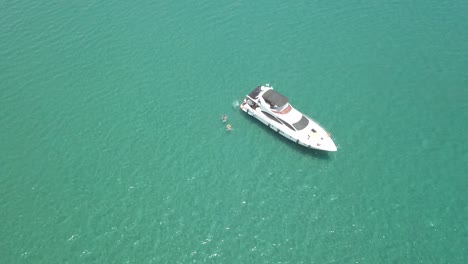 Drohne-Steigt-Hoch-Von-Einer-Schönen-Weißen-Yacht,-Menschen-Schwimmen-Daneben,-Zypern