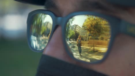 Girl-walking-in-park-reflection-in-man's-sunglasses-on-Summer-day