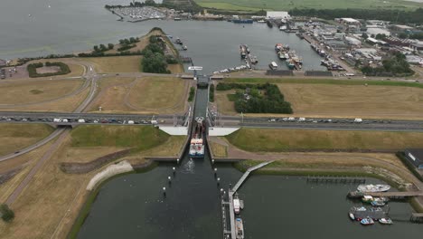 Vessel-enters-Haringvliet-sea-lock-as-cars-wait-patiently-on-highway,-Stellendam