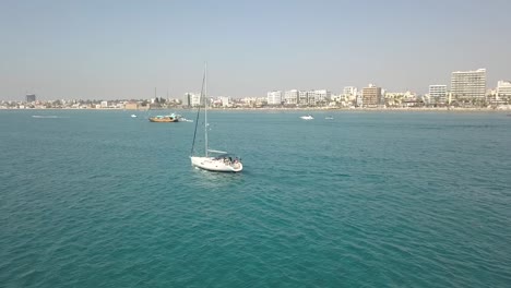 Coming-Into-Shot-Of-Stunning-scenery-Of-Sailing-Boat-With-Larnaca-Cityscape,-Cyprus