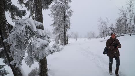 Hombre-Caucásico-Con-Ropa-Informal-De-Invierno-Caminando-Por-Un-Camino-Forestal-Invernal-Cubierto-De-Nieve-Espesa