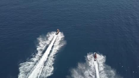 Tracking-Shot-Of-Two-Persons-On-Jet-Ski-Riding-Side-To-Side-In-Open-Blue-Sea,-Cyprus