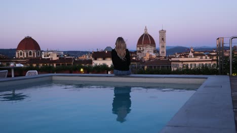 Female-Tourist-by-Rooftop-Pool-at-Sunset-overlooking-Beautiful-Florence,-Italy