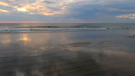 Tilt-up-beach-to-ocean-at-sunrise-low-tide