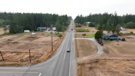 Drone-shot-tracking-a-car-driving-down-a-rural-highway-on-Whidbey-Island