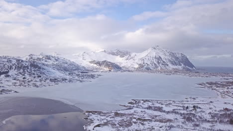 Aerial-shot-over-a-frozen-lake-and-mountains-in-Lofoten-Islands,-Norway
