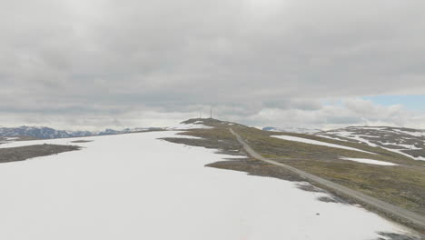 Montaña-Storhovd-Semi-Cubierta-De-Nieve-En-Noruega-En-Un-Día-Nublado,-Mástil-De-Teléfono-Distante