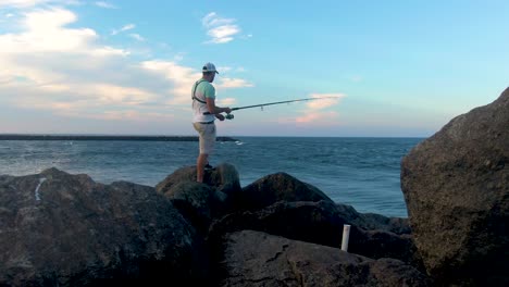Hombre-Pescando-En-La-Playa-De-Plum-Island,-Vista-Trasera