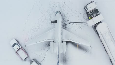 Refueling-of-private-business-jet-airplane-with-snow-covered-tarmac,-aerial