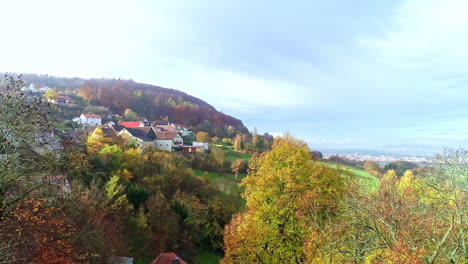 Beautiful-shot-revealing-German-town-and-landscape-surrounded-with-Autumn-trees,-Aerial-shot