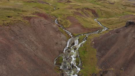 Aerial-small-stream-waterfall-in-Iceland-in-the-brown-and-green-mountains