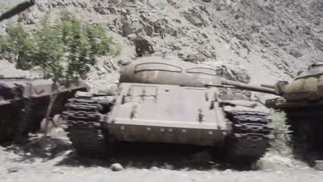 Destroyed-Soviet-produced-tanks-in-Panshir-valley,-driving-past-handheld-view