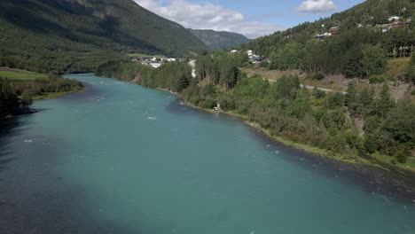 Aerial-drone-shot-from-right-to-left-over-Otta-river-flowing-through-rural-countryside-in-Lom,-Norway-at-daytime