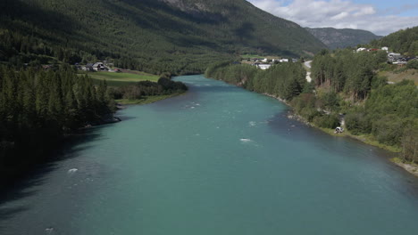 Aerial-drone-forward-moving-shot-over-Otta-river-flying-along-rural-countryside-in-Lom,-Norway-at-daytime
