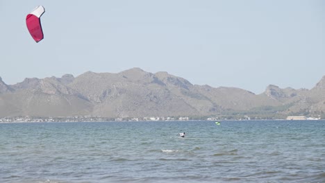 Kiteboarding-in-cear-blue-water-Mallorca-Balearic-Islands-surrounded-by-mountain