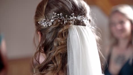 Adjusting-bridal-veil-of-bride-with-curly-brown-hair-before-wedding