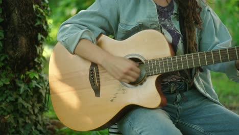 Acoustic-guitar-closeup-female-artist-playing-outside