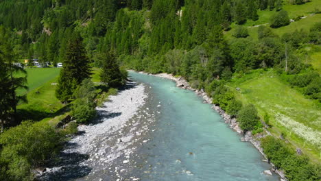 beautiful-natural-scenery-of-turquoise-blue-freshwater-flowing-downstream-with-white-rocks-on-riverbank-during-summer,-aerial-landscape
