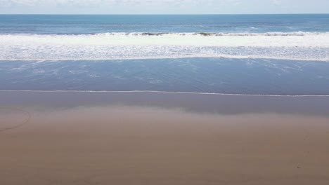 Big-waves-crashing-onto-an-empty-flat-beach-in-broad-daylight