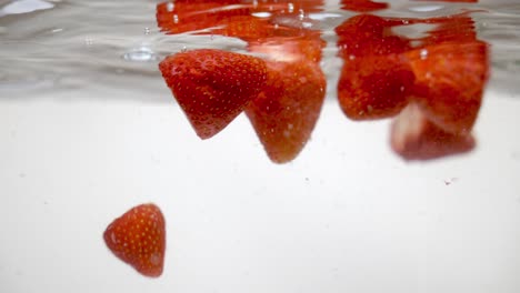Fresh-red-strawberries-floating-on-water-surface,-underwater-shot