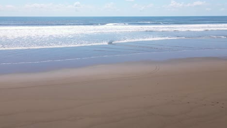 Bright-blue-ocean-waves-crashing-on-calm-beach-on-the-shores-of-Costa-Rica