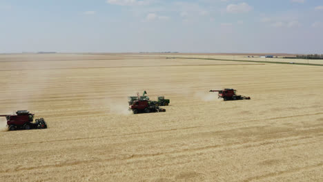Aerial-parallax-around-combines-harvesting-grain-in-Saskatchewan,-Canada