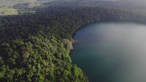 Vista-Desde-Arriba-Del-Lago-Eacham-Con-Exuberante-Selva-Tropical-En-Atherton-Tableland,-Queensland,-Australia---Tiro-De-Drones