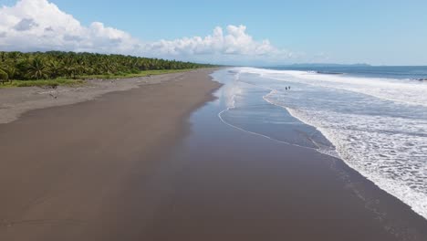 Vuelo-De-Drones-A-Lo-Largo-De-Una-Extensa-Playa-Tropical-Con-Solo-Unas-Pocas-Personas-De-Pie-En-Las-Cálidas-Aguas-Del-Pacífico-Sur