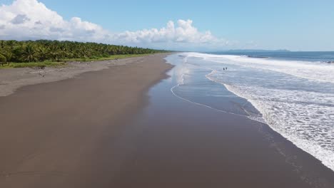 Drone-flight-along-an-expansive-tropical-beach-with-only-few-people-standing-in-the-warm-water-of-the-south-pacific