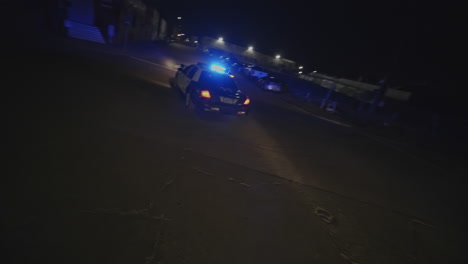 Filmische-Zeitlupenaufnahme-Von-Zwei-Polizeiautos,-Die-Nachts-Ein-Auto-überfahren