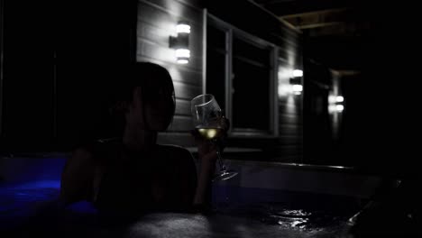 Retrato-Femenino-En-La-Oscuridad-Relajándose-En-El-Jacuzzi-Y-Bebiendo-Vino-Por-La-Noche