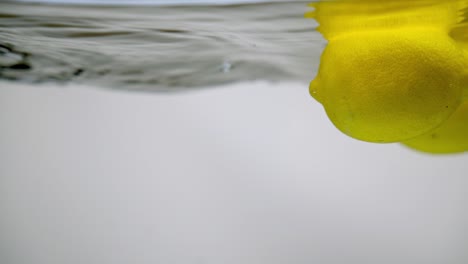 Yellow-lemon-citrus-fruits-floating-in-water-surface,-space-for-text