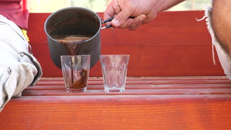 pouring-coffee-in-glass-cups-during-chit-chat-outdoors,-close-up-static-shot